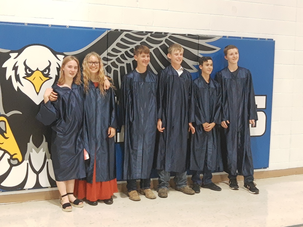 Students standing in front of a blue mat with an eagle on it. 
